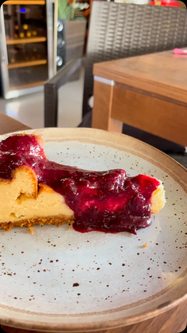 Fatia de cheesecake com compota de frutos vermelhos num prato de cerâmica