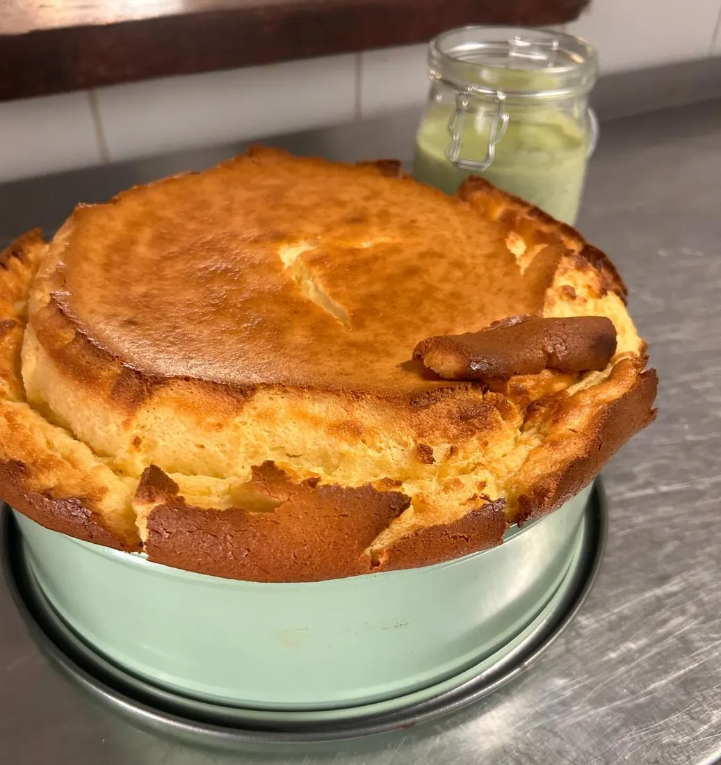 Cheesecake acabado de sair do forno, alto e dourado, ainda na forma