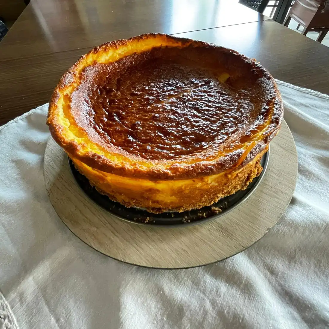 Cheesecake inteiro com topo dourado, pousado na mesa